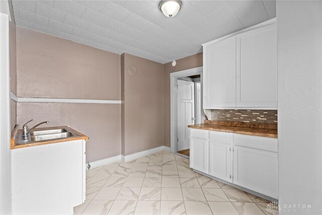 kitchen with tasteful backsplash, sink, and white cabinets