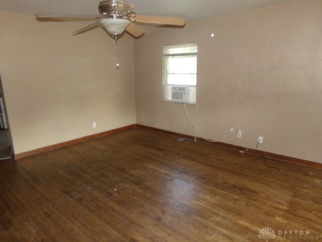 empty room featuring ceiling fan, cooling unit, and dark hardwood / wood-style flooring