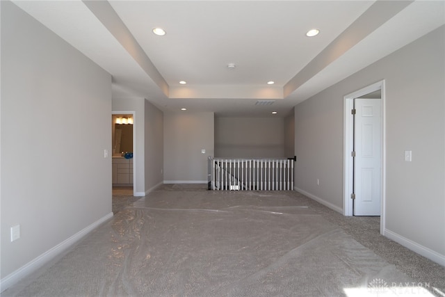 carpeted empty room featuring a raised ceiling