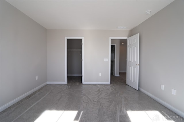 unfurnished bedroom with a closet, a walk in closet, and carpet flooring