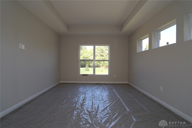 unfurnished room featuring dark colored carpet and a raised ceiling