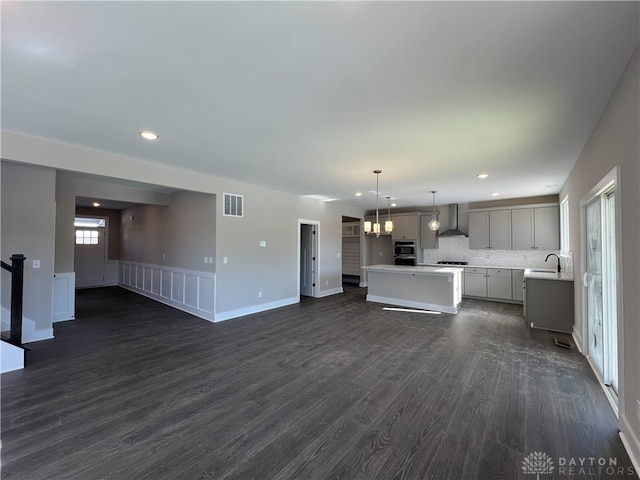 unfurnished living room with dark hardwood / wood-style flooring, sink, and a notable chandelier