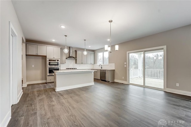 kitchen with gray cabinets, a kitchen island, dishwasher, hanging light fixtures, and wall chimney range hood