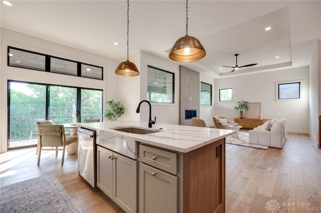 kitchen with sink, light stone counters, a healthy amount of sunlight, and decorative light fixtures