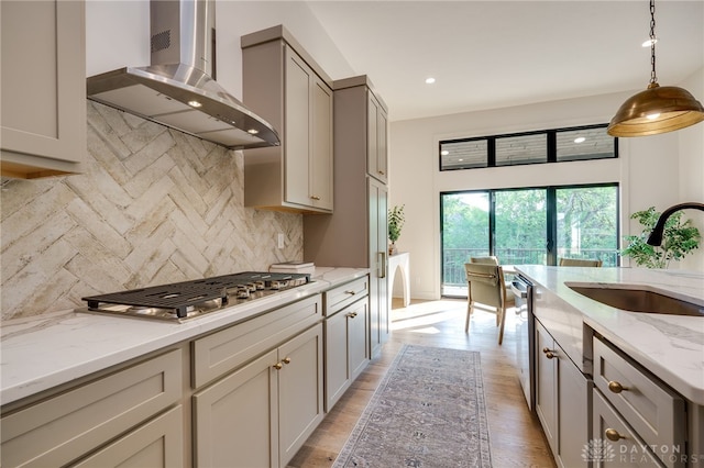 kitchen with decorative backsplash, wall chimney range hood, sink, gray cabinets, and light hardwood / wood-style floors