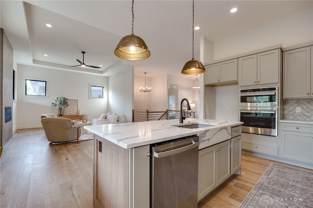 kitchen featuring sink, light stone counters, stainless steel appliances, and light hardwood / wood-style floors