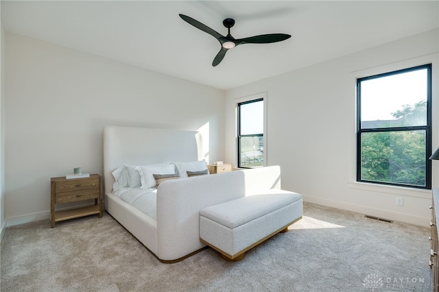 bedroom featuring light carpet, multiple windows, and ceiling fan