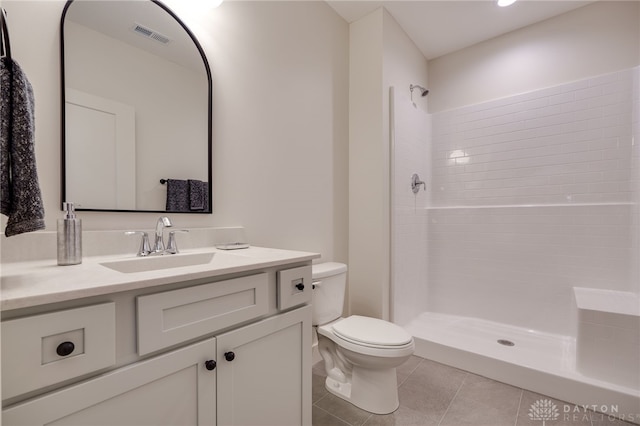 bathroom featuring vanity, tiled shower, toilet, and tile patterned flooring