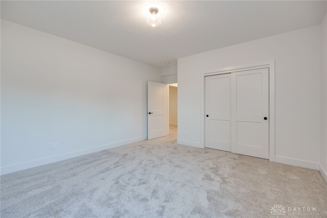 unfurnished bedroom featuring a closet and light colored carpet