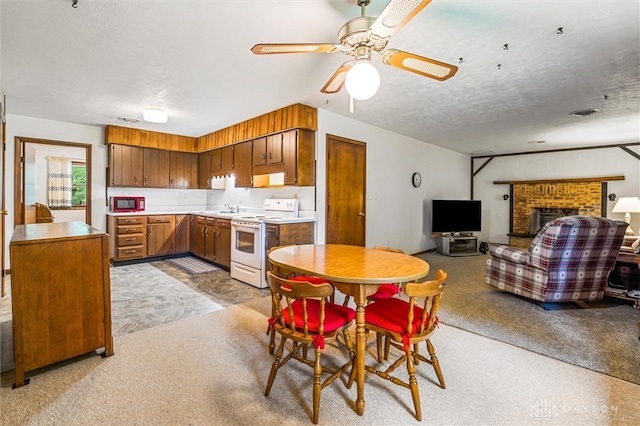 dining space with a textured ceiling, a brick fireplace, sink, and ceiling fan