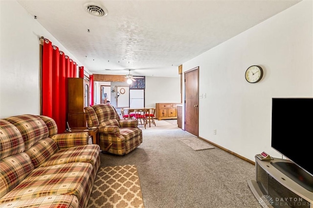 living area featuring visible vents, baseboards, a ceiling fan, and carpet floors