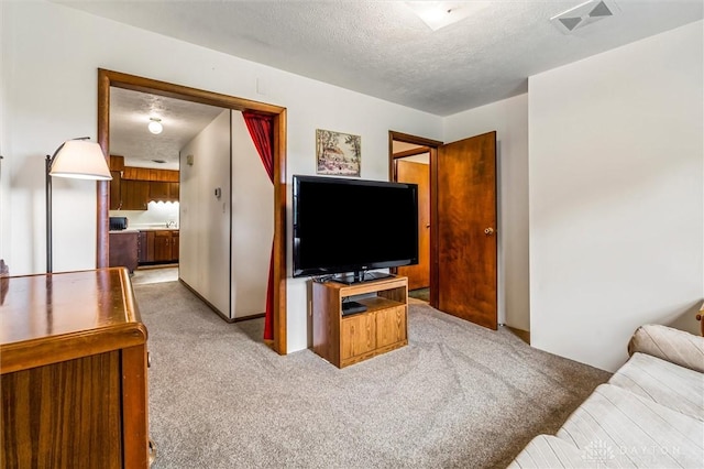 living room featuring a textured ceiling, light colored carpet, and visible vents