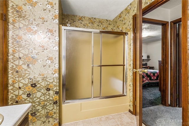 bathroom featuring combined bath / shower with glass door, tile patterned floors, vanity, and a textured ceiling