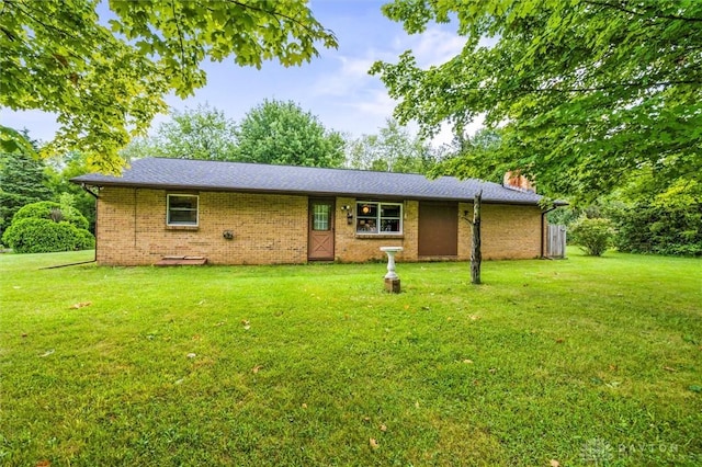 exterior space featuring brick siding, a lawn, and a chimney