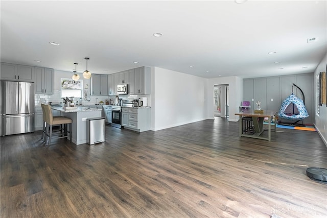 kitchen with dark hardwood / wood-style flooring, stainless steel appliances, a kitchen island, and gray cabinetry