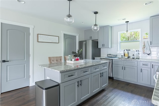 kitchen featuring appliances with stainless steel finishes, sink, pendant lighting, gray cabinets, and dark hardwood / wood-style floors