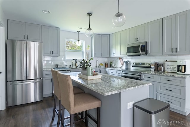 kitchen featuring light stone countertops, a center island, stainless steel appliances, and dark hardwood / wood-style floors