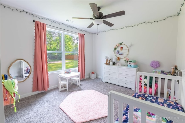 carpeted bedroom with ceiling fan and a nursery area