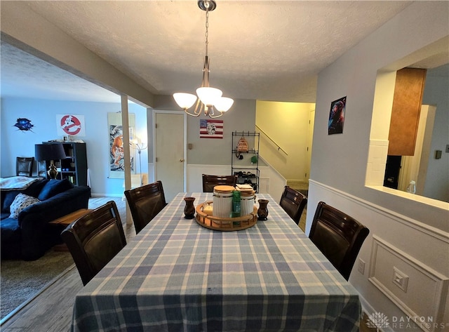 dining room featuring wood-type flooring, a textured ceiling, and a notable chandelier