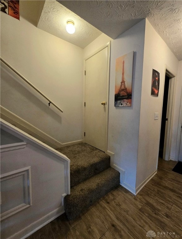 stairway with hardwood / wood-style floors and a textured ceiling