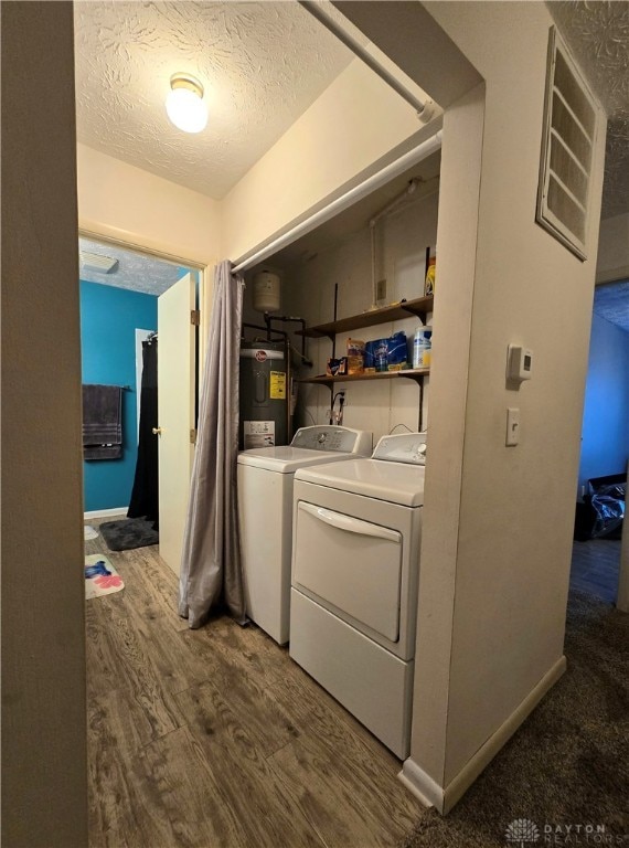 washroom featuring hardwood / wood-style floors, washing machine and clothes dryer, a textured ceiling, and water heater