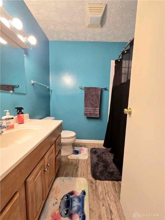 bathroom with hardwood / wood-style floors, a textured ceiling, toilet, vanity, and a shower with shower curtain