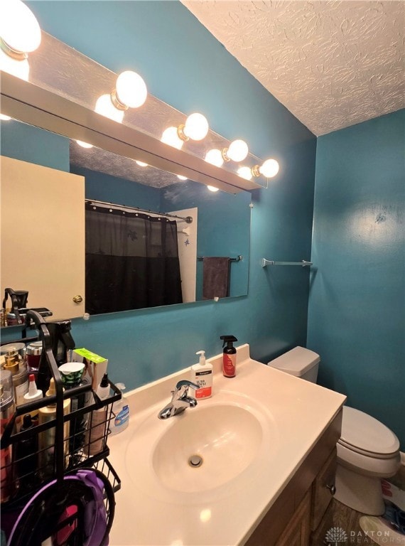 bathroom with vanity, a textured ceiling, toilet, and curtained shower