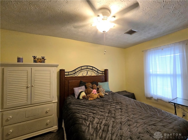 bedroom with ceiling fan and a textured ceiling