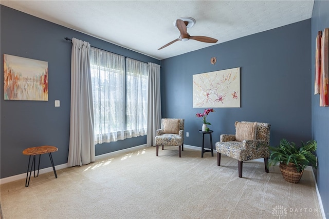 living area featuring carpet floors, a textured ceiling, and ceiling fan