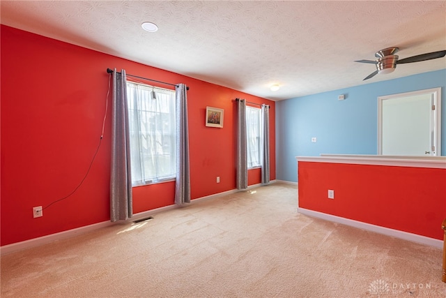 empty room featuring light colored carpet, a wealth of natural light, and ceiling fan