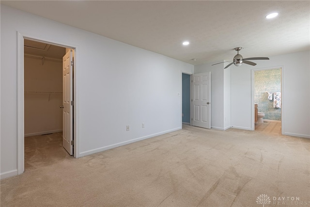 unfurnished bedroom with a spacious closet, ceiling fan, a closet, and light colored carpet