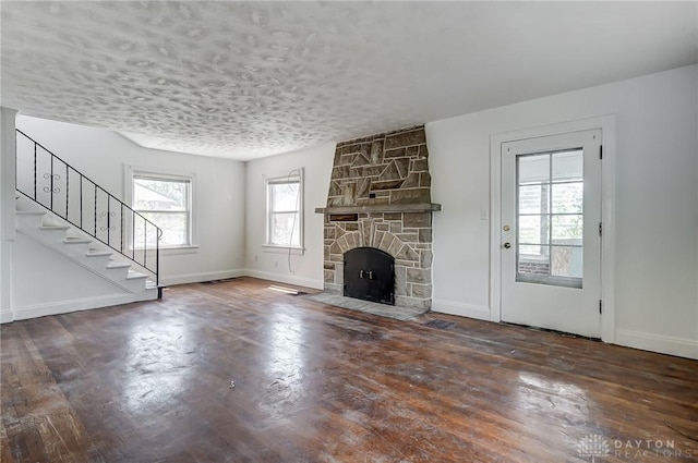 unfurnished living room with a textured ceiling, a fireplace, baseboards, stairs, and dark wood-style floors