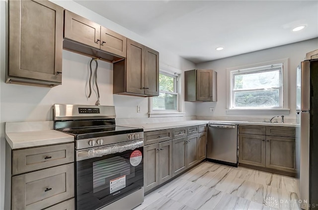 kitchen with appliances with stainless steel finishes, light countertops, a sink, and recessed lighting