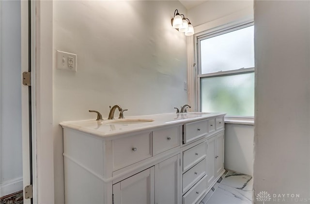 full bath with marble finish floor, double vanity, and a sink