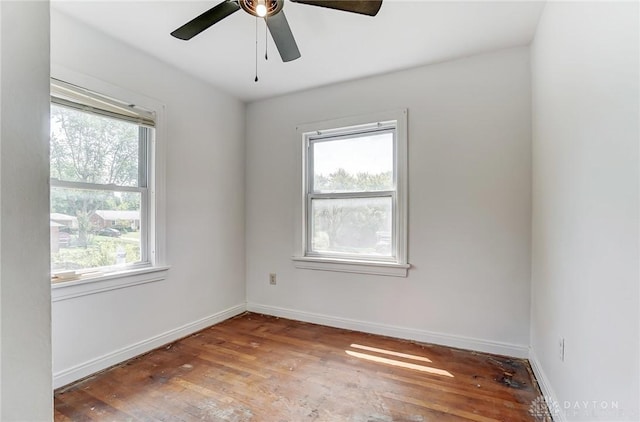 unfurnished room with ceiling fan, wood finished floors, a wealth of natural light, and baseboards