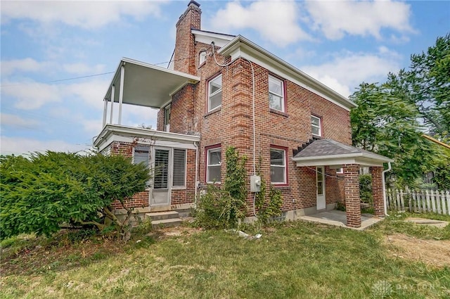 exterior space with a front lawn, a chimney, and brick siding