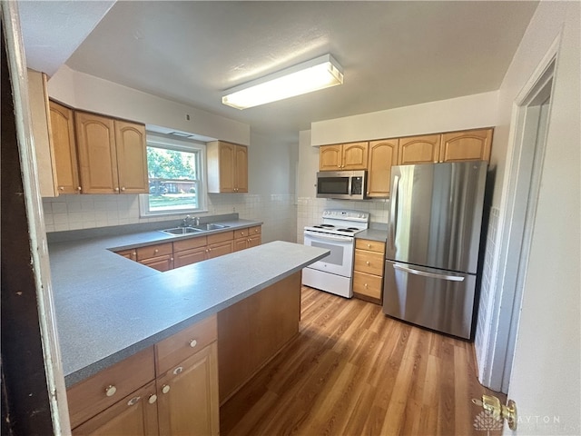 kitchen featuring decorative backsplash, light wood-type flooring, sink, appliances with stainless steel finishes, and kitchen peninsula