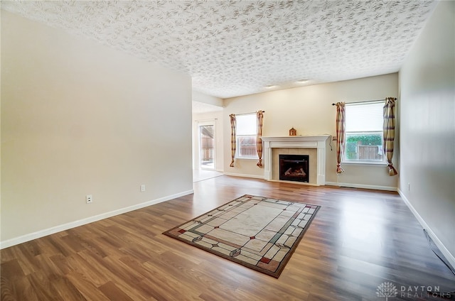 unfurnished living room featuring a fireplace, a textured ceiling, and dark hardwood / wood-style flooring