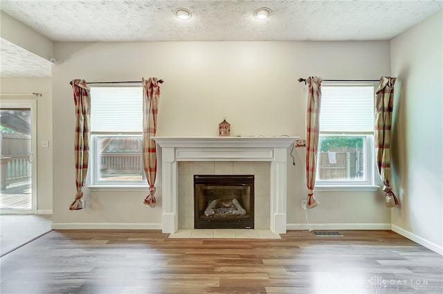 unfurnished room featuring a fireplace, a textured ceiling, and light wood-type flooring