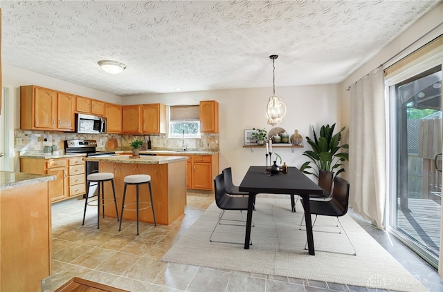 kitchen with a center island, hanging light fixtures, tasteful backsplash, a breakfast bar area, and appliances with stainless steel finishes