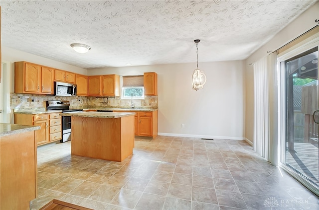 kitchen featuring pendant lighting, backsplash, a textured ceiling, appliances with stainless steel finishes, and a kitchen island