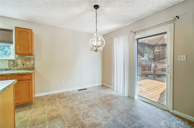 unfurnished dining area with a textured ceiling and a chandelier