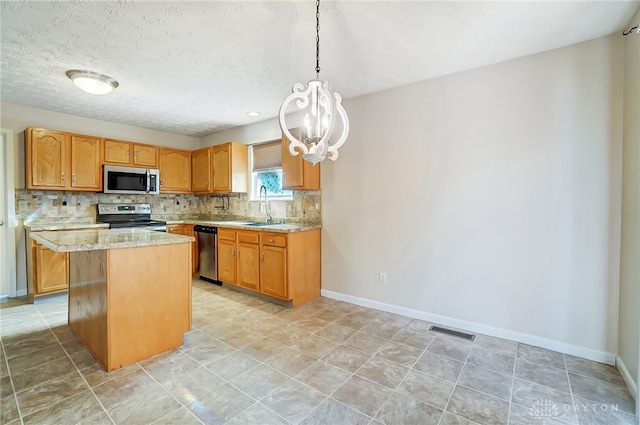 kitchen with sink, tasteful backsplash, pendant lighting, a kitchen island, and appliances with stainless steel finishes