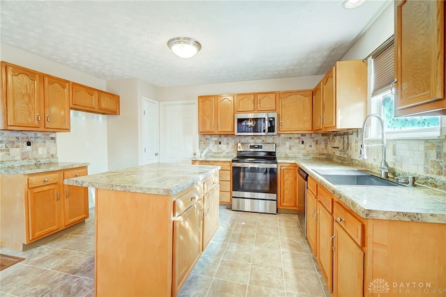 kitchen with decorative backsplash, appliances with stainless steel finishes, a kitchen island, and sink