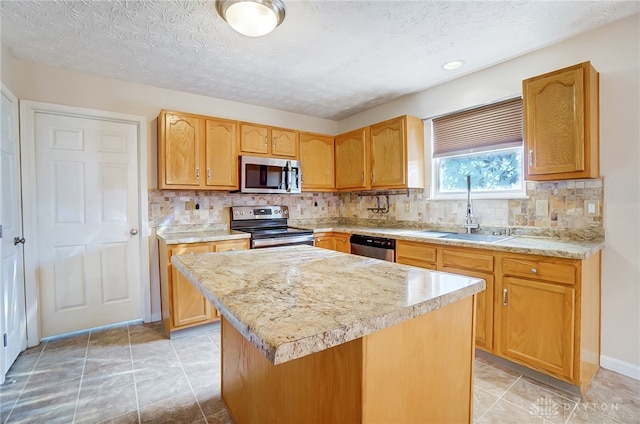 kitchen with appliances with stainless steel finishes, tasteful backsplash, a textured ceiling, sink, and a kitchen island