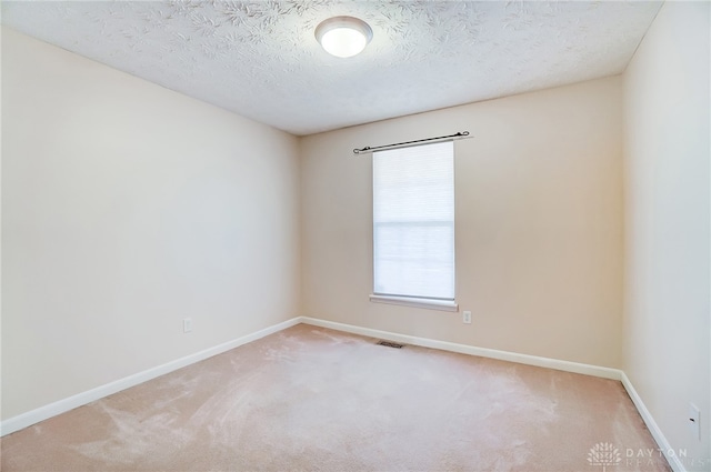 empty room featuring light carpet and a textured ceiling