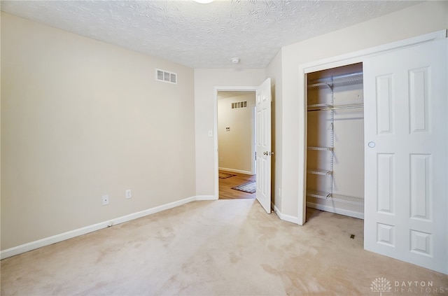 unfurnished bedroom featuring a closet, light colored carpet, and a textured ceiling