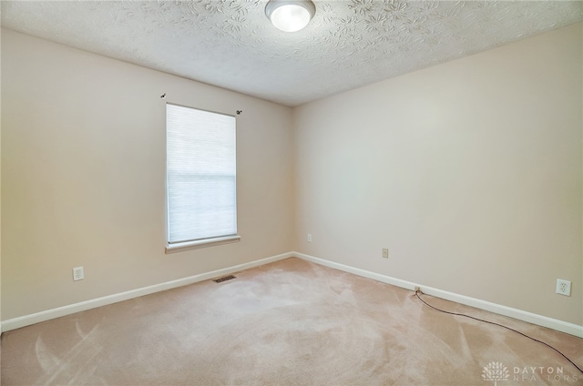 empty room with carpet and a textured ceiling