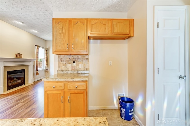 kitchen with tasteful backsplash, a textured ceiling, and light hardwood / wood-style flooring