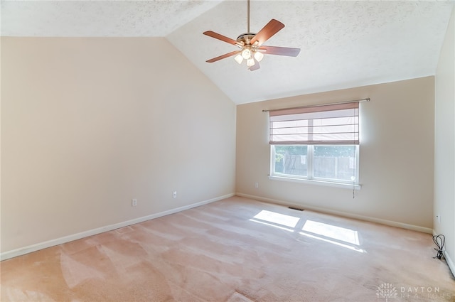 empty room with a textured ceiling, light carpet, and vaulted ceiling